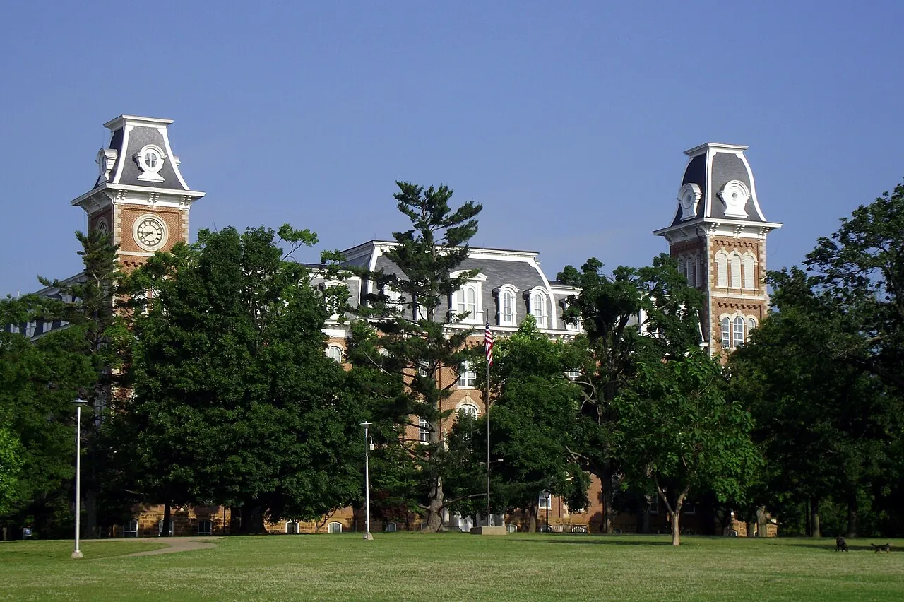 Old Main towers rising above trees and lawns in Fayetteville